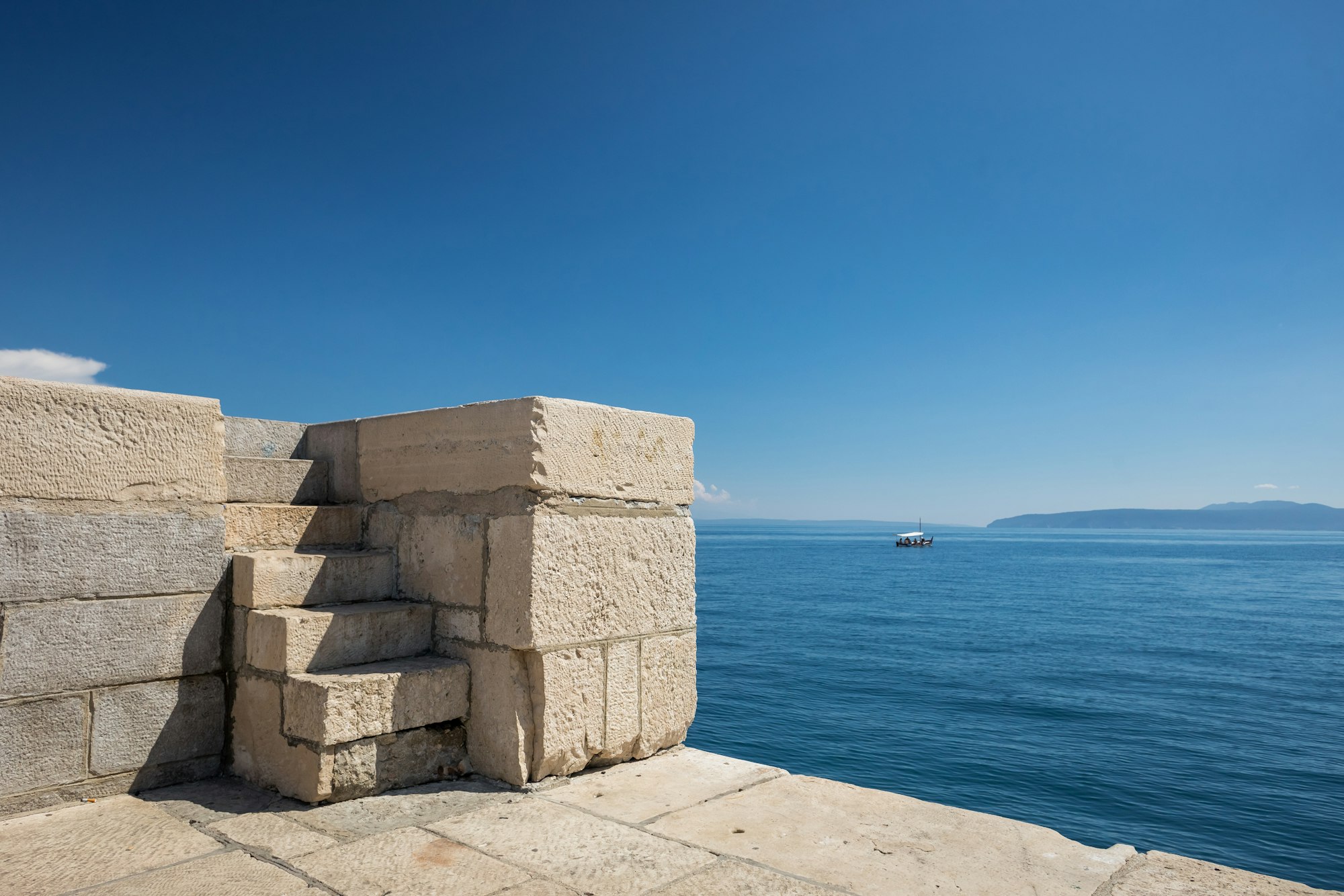 View of old concrete blocks in the bay of Lovran, Croatia on a blue sky background