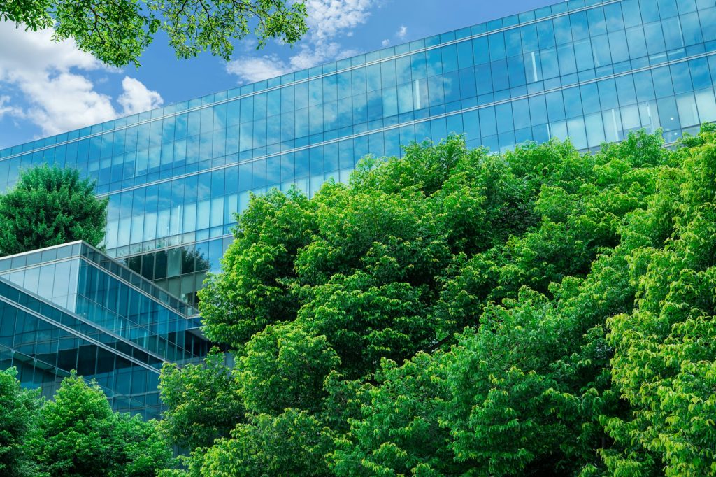 Eco-friendly building in modern city. Sustainable glass office building with trees for reducing CO2.