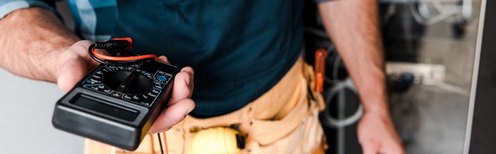 panoramic shot of technician holding digital meter