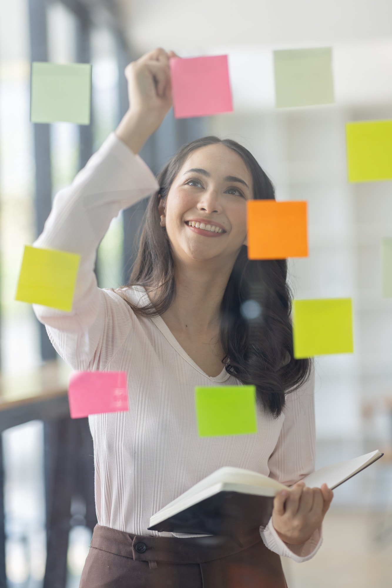 Business female employee with many conflicting priorities arranging sticky notes commenting and brai
